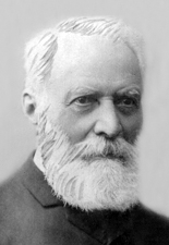 Black and white photograph of the head of an old man with a beard.