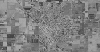 A low-contrast black-and-white satellite image of a small city and surrounding farm land