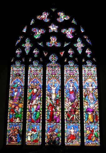 This stained glass window is divided into five long sections, above which the stone tracery looks like a lacey medallion. The colours are not like Medieval glass; there is a lot of bright red, pale blue, apple green, mauve and pink.