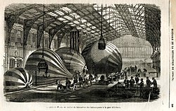 Black-and-white drawing of balloons assembled under the glass roof of a train station.
