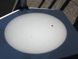 White disk with a small black dot projected on a screen