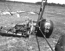 The shattered remains of a small helicopter-like craft lay on their side on the ground following an accident.