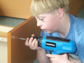 File:A boy with Down syndrome using cordless drill to assemble a book case.jpg