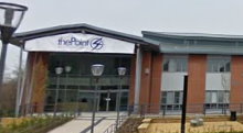 A large brick building with a glass fronted entrance which has an apex roof; above the entrance is a sign saying "thePoint4"; a concrete drive leads up to the building.
