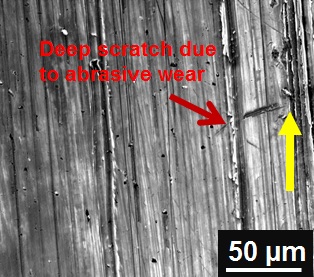 File:Deep 'groove' like surface indicates abrasive wear over cast iron (yellow arrow indicate sliding direction).jpg