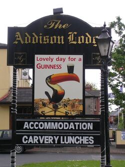 A sign for a hotel with an advertisement featuring a toucan with a cup of beer on its beak and text saying "Lovely day for a GUINNESS"