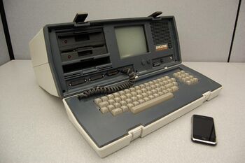 Large early portable computer next to a modern smartphone