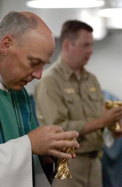 US Navy 030727-N-8148A-100 Lt. Richard House, Assistant Command Chaplain, (left) and Lt. Chris Chandler offer Holy Communion during the first underway Roman Catholic Mass aboard USS Ronald Reagan (CVN 76).jpg