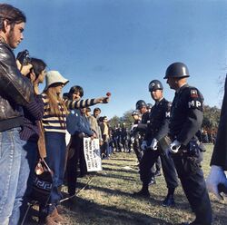 A young woman demonstrator offers a flower to a military police officer at the March on the Pentagon, 1967