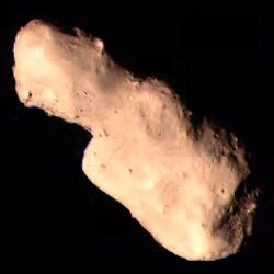 Photograph of an elongated, rocky asteroid, on the black background of space, taken by a space probe.