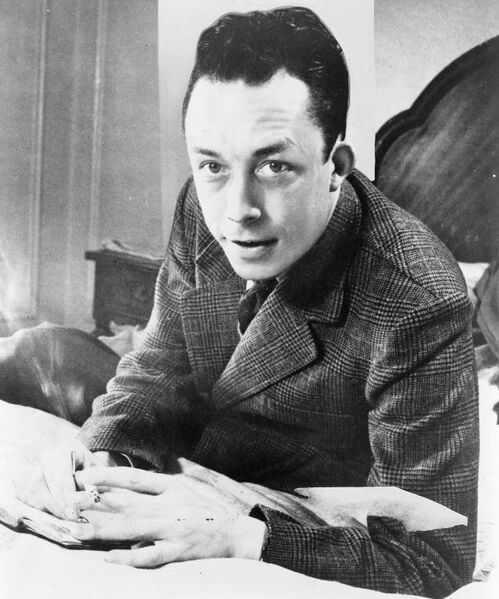 File:Albert Camus, gagnant de prix Nobel, portrait en buste, posé au bureau, faisant face à gauche, cigarette de tabagisme.jpg