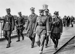 A general walks in military uniform flanked by other officers