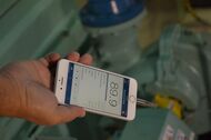 An image of a person holding a smartphone displaying the NIOSH sound level meter application (app)