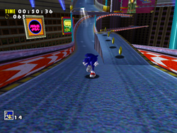 Gameplay screenshot of Speed Highway, one of the levels in Sonic Adventure. In this image, Sonic runs on a road, to a line of rings. The HUD shows a timer, the amount of rings, and the player's lives.