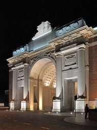 A triumphal arch made of red brick and limestone illuminated at night.