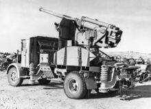 An Italian 90-53 gun on a truck mounting joining the rows of derelict Axis vehicles and equipment jettisoned by Rommel's army.jpg