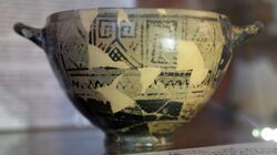 Photograph of a Greek pot in a museum case.