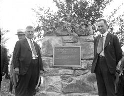 two men standing by a stone pillar with a bronze historical marker for the York Imperial apple