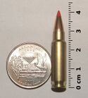 Photo of a 5.7×28mm SS196SR cartridge next to a quarter and ruler, in a size comparison.