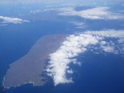 Aerial photo of Kahoʻolawe. In the background is Mount Haleakala on Maui