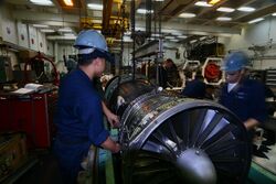 US Navy 050617-N-6009S-001 Sailors assigned to the Aircraft Intermediate Maintenance Department (AIMD) jet shop lower a F-A-18 Hornet engine into its container.jpg