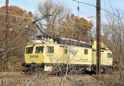 A railway work vehicles in bright yellow paint with a blue Amtrak logo