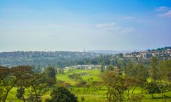 Panorama photograph with the greens and buildings of the golf club visible, as well as hills and houses in the distance