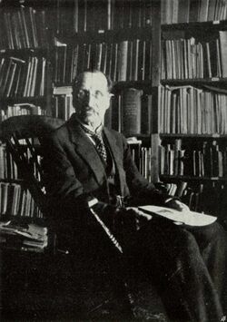 Distinguished-looking man sitting in an office, surrounded by books