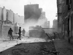 M18 tank destroyer fires its 90mm gun point-blank at a Nazi pillbox emplacement to clear a path through a side street in Brest, France. September, 1944. (49811749312).jpg