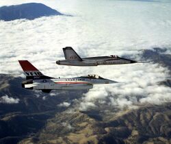 Two jet aircraft flying together over mountain range and cloud