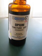 Orange transparent bottle labelled "opium tincture USP (deodorized)." There is a warning label declaring the product to be poisonous.