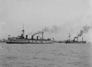 Two warships with steam rising from their smokestacks at anchor off New York harbor