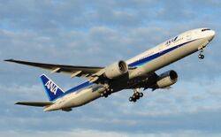 Aircraft takeoff. Quarter view of aircraft ascending in the sky, with landing gear still deployed.