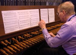 A man plays a carillon's wooden keyboard with his fists.