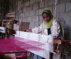 An Ethiopian woman, a member of FWFCA, working at a loom