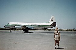 A plane on the tarmac at an airport with a man in the foreground