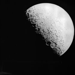 A black-and-white image of Earth's Moon. The terminator is visible as the lower left of its surface is in shadow.
