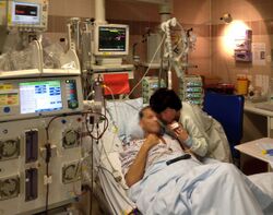 Patient lying in bed in intensive care unit of hospital with apparatuses and hemodialysis machine.jpg