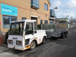 Small, white utility vehicle with a trailer attached