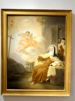 A barefoot nun looking up to angels and a dove. She sits by a table. Other nuns enters through a side door.