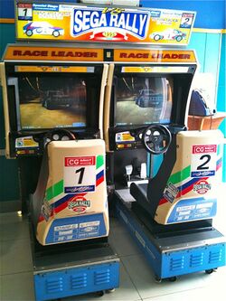 An arcade cabinet with two seats and steering wheels