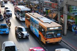 A partial view of a road with many vehicles, including buses, cars, taxis and motorcycles