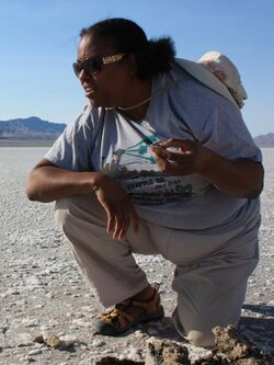 A photo of Dr. Kennda Lynch in the field, examining materials in an ancient lake bed