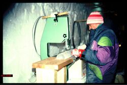 Scientist standing at a bench, sawing an ice core