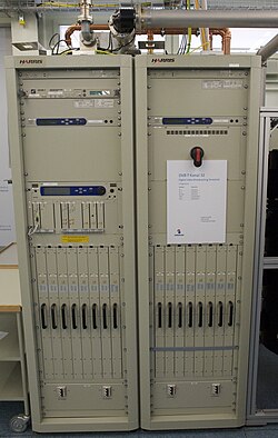 Electronics equipment, light gray in color, taking up two racks in a utility room.