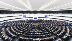 Rows and rows of people are assembled circularly in a huge chamber at the European Parliament