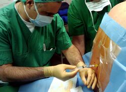 A man injects a clear liquid through a tube into the patient's spine