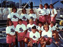Group shot of thirteen women wearing white T-shirts and pink shorts on board a yacht