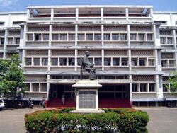 Large white building with a statue of a seated figure in front