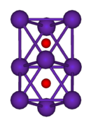 The ball-and-stick diagram shows two regular octahedra which are connected to each other by one face. All nine vertices of the structure are purple spheres representing rubidium, and at the centre of each octahedron is a small red sphere representing oxygen.